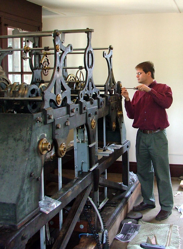 Man using a screwdriver on a large and elaborate piece of machinery