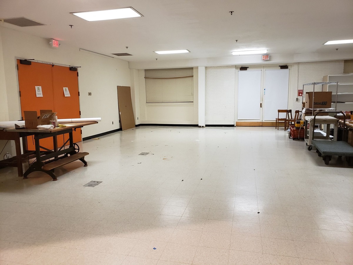 Room with orange double doors on one wall and white double doors on another, with table on one side and other items in a clump on the other