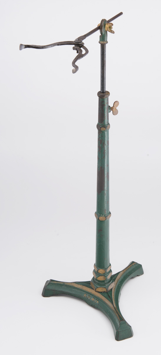 Green and gold metal stand with rounded gold metal piece at top