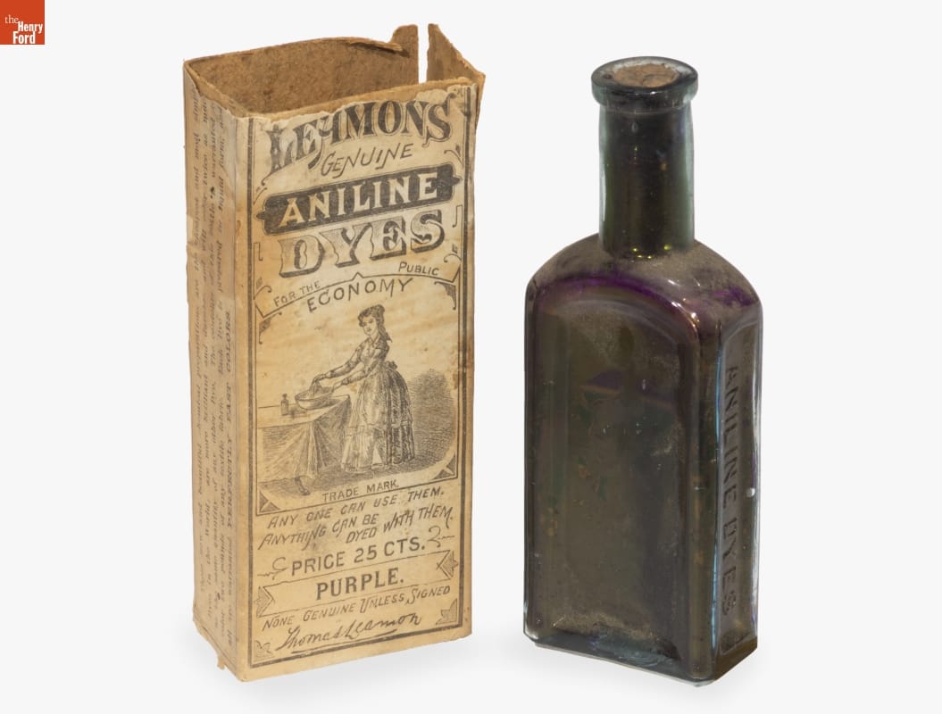 Purple glass bottle sitting next to box with images and text