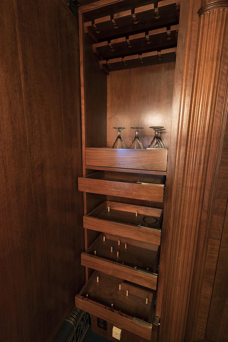 Wooden shelving with pegs on some shelves and a few glasses on top shelf