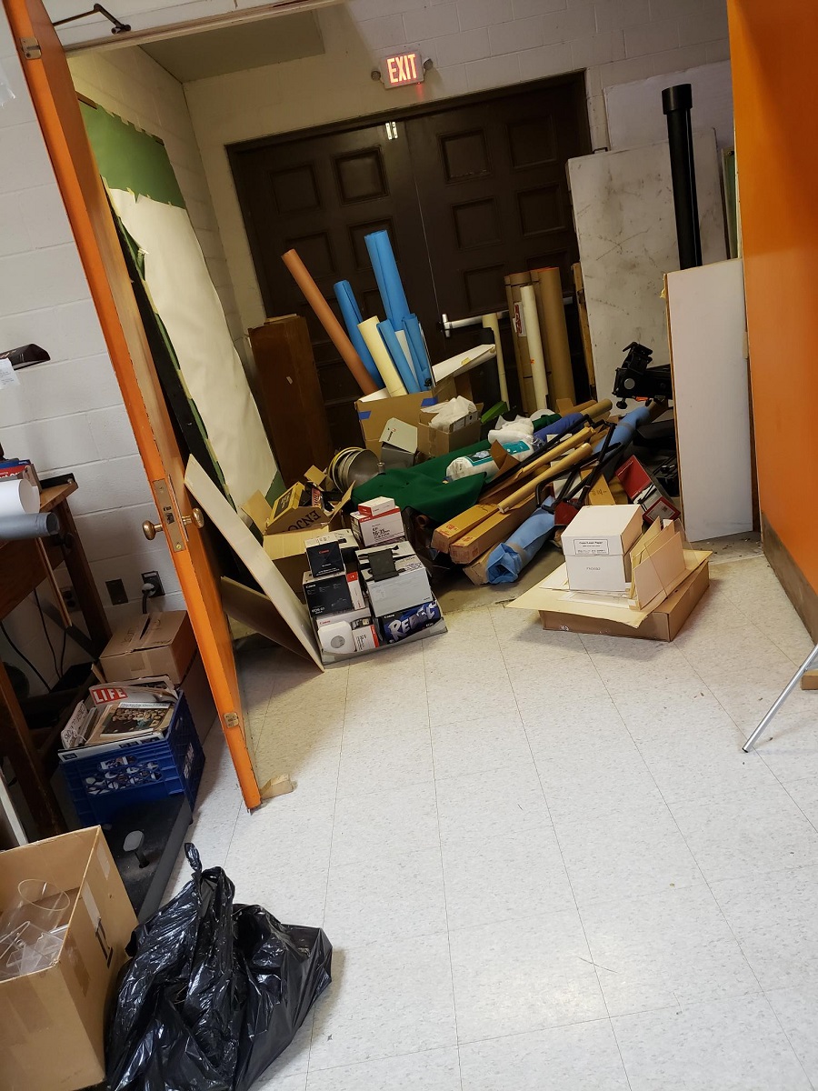 Space by large doubledoor cluttered with rolls, boxes, and other items