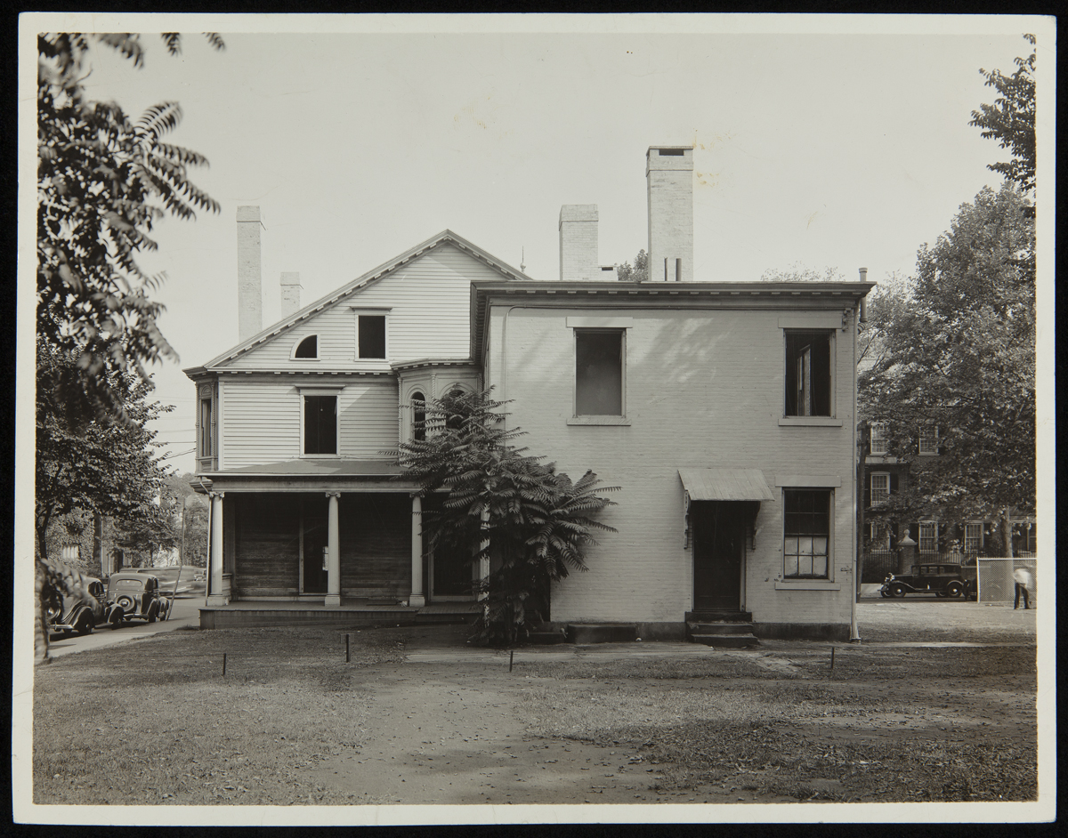 Back of home with lawn behind and trees on either side