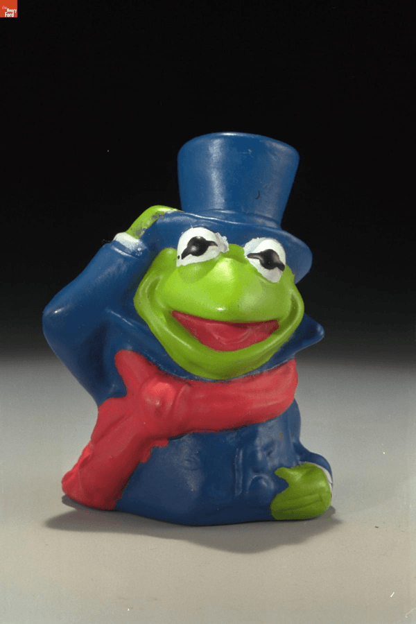 Muppet Christmas Carol Kids' Meal Toys GIF cycling through toy images: frog in top hat and scarf, pig in dress and bonnet, and blue creature with hooked nose in yellow top hat and holding a book