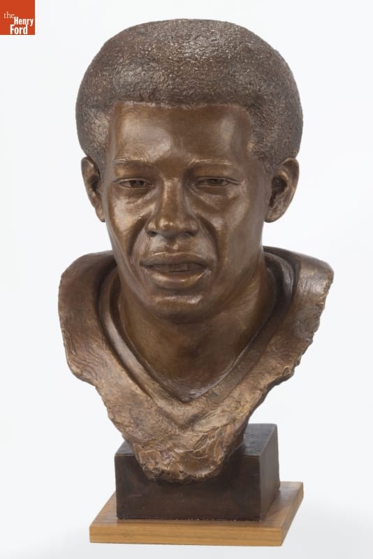 Sculpture of face and partial torso of man with Afro on square base