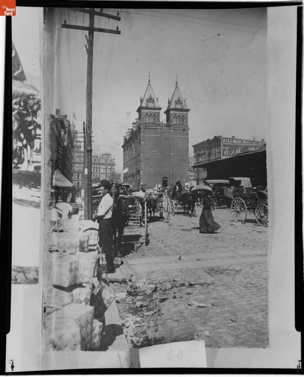 Street scene with people, horses and carriages, and buildings