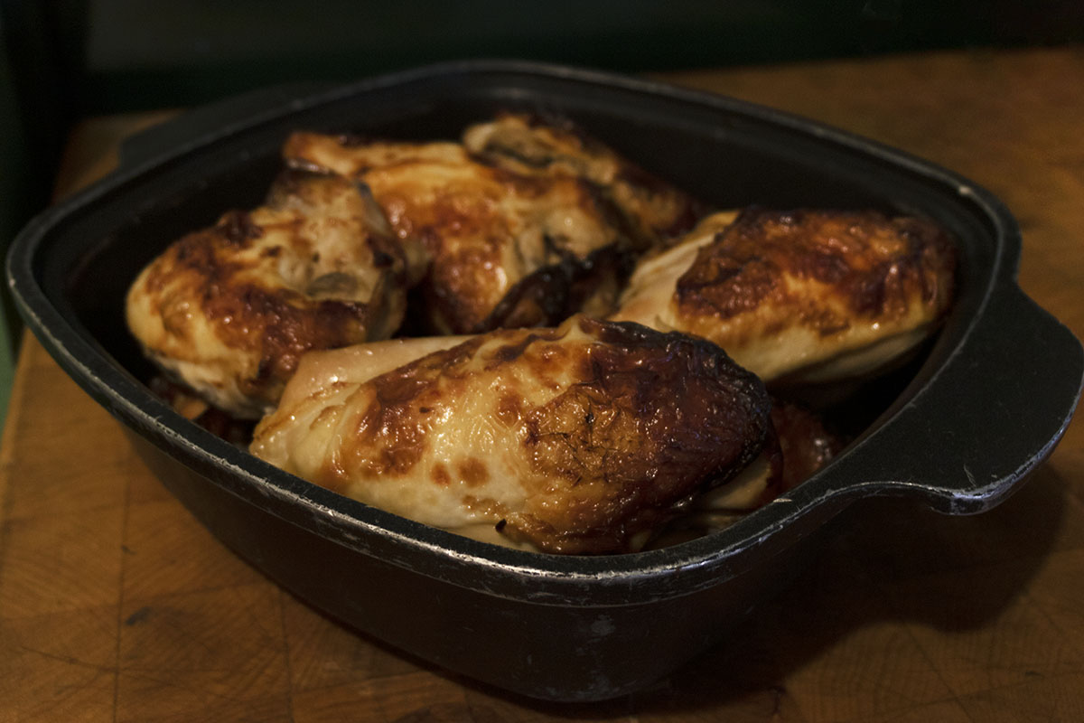 Brined and Roasted Chicken Four roasted chicken breasts in a cast iron dish on a butcher's block