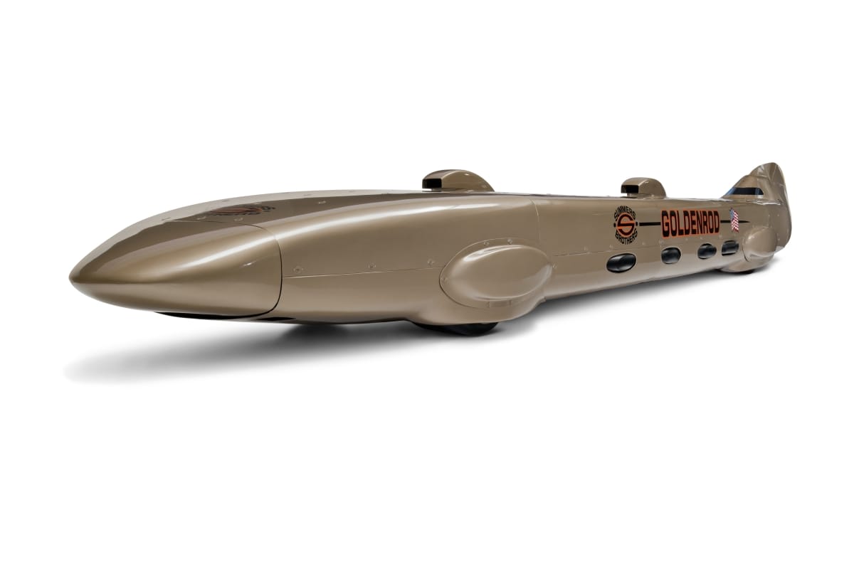 Very long, low golden race car with text on side