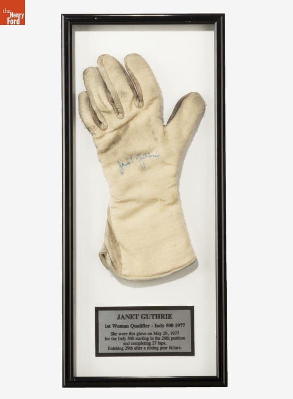 White glove in black frame with gold plaque containing text below it