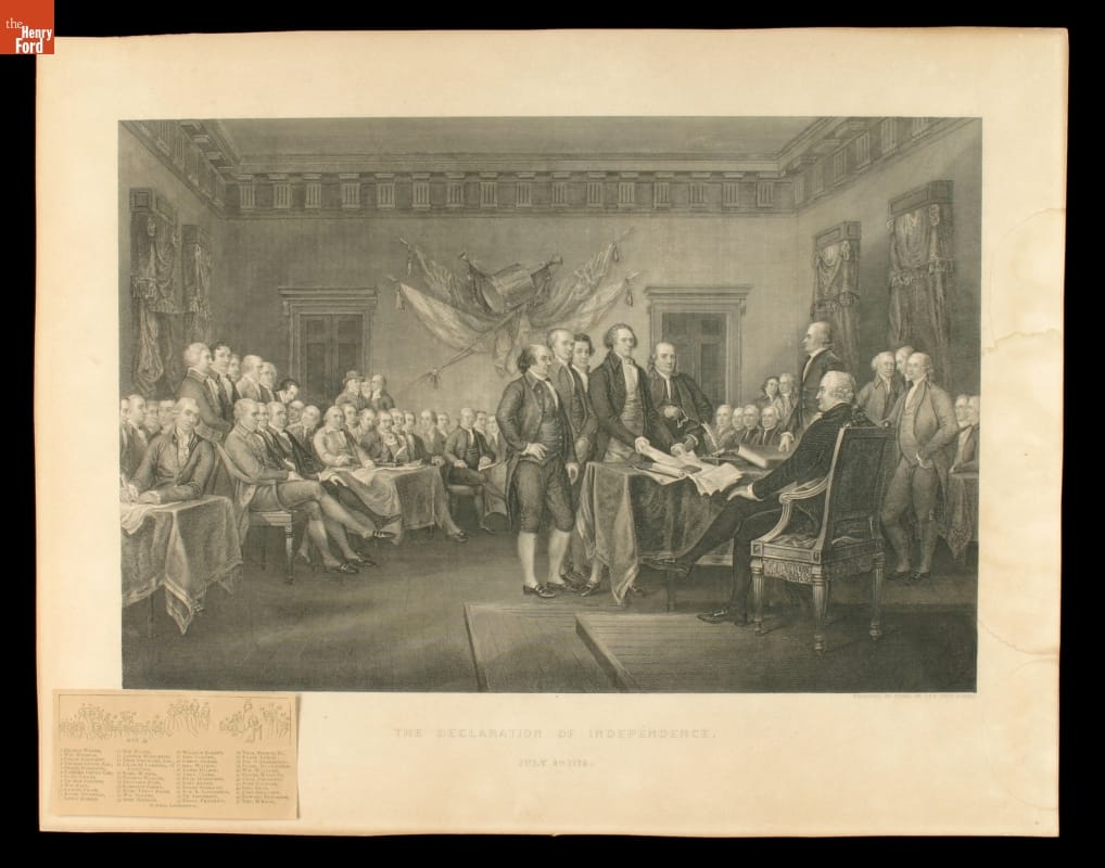 Black-and-white print of a group of men in a room looking towards a table with five men standing before a seated man 