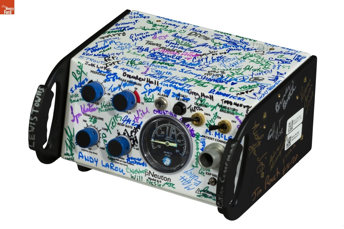 Black-and-white equipment with dials, switches, and gauges, covered in signatures in various colors