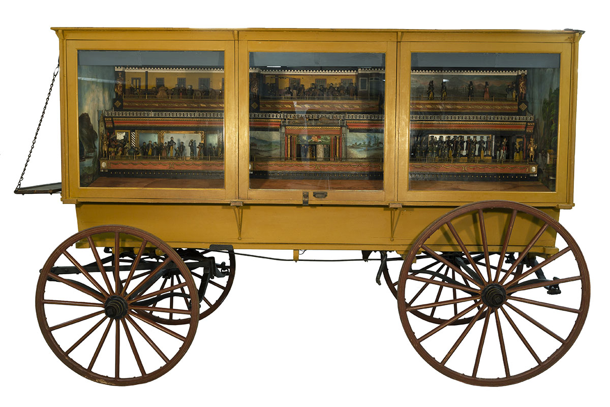 "The Busy World" Automaton, 1830-1850 Mustard yellow wagon with three glass doors on side; miniature scenes visible inside doors