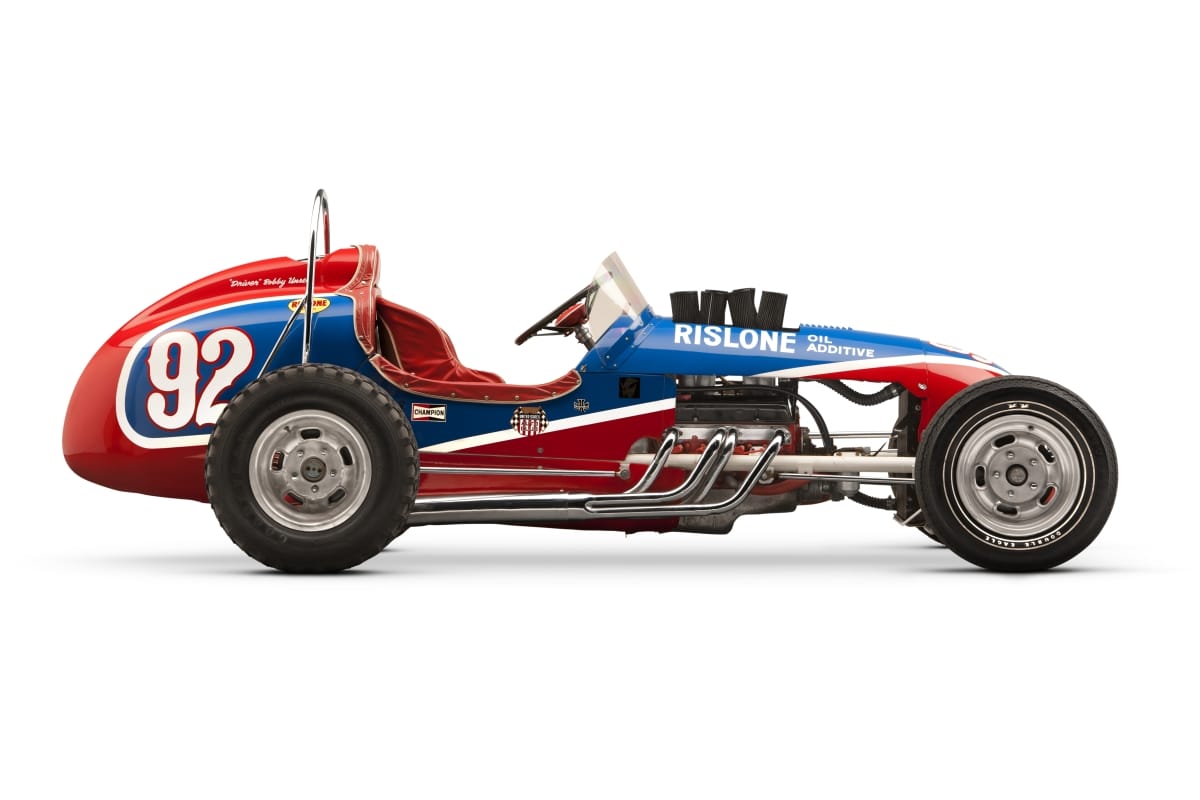 Side view of red, blue, and white open cockpit race car with large "92" and other text on side