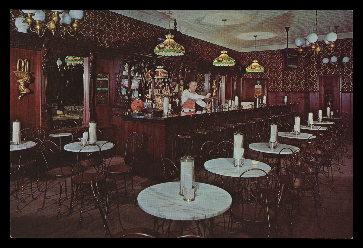 Elaborately decorated Victorian-style ice cream parlor with small marble tables and wire chairs