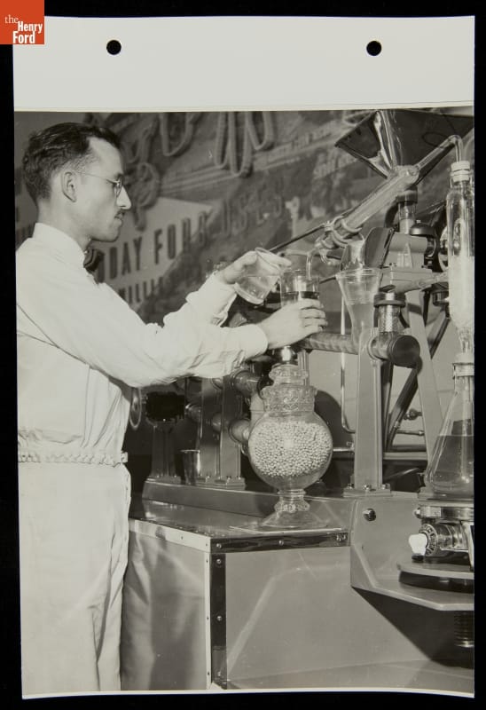 Soybean Processing for Fiber and Oil, Ford Exposition, New York World's Fair, 1939 A man holds beakers of liquid up to an apparatus