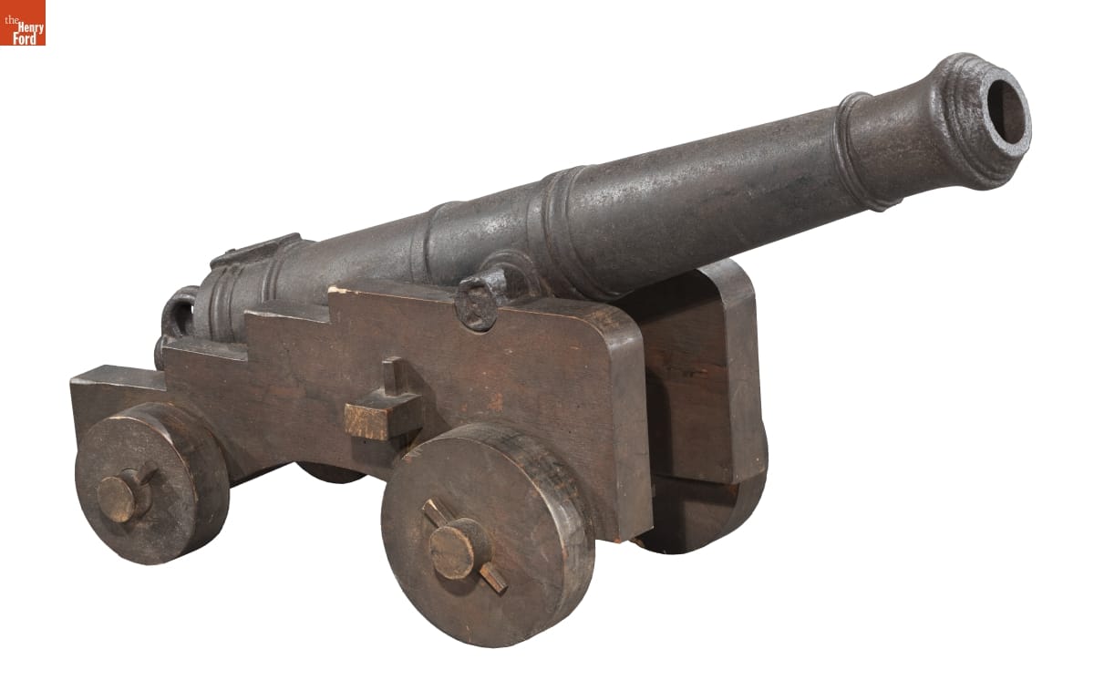 Metal cannon with some decorative banding, mounted on a metal (?) cart