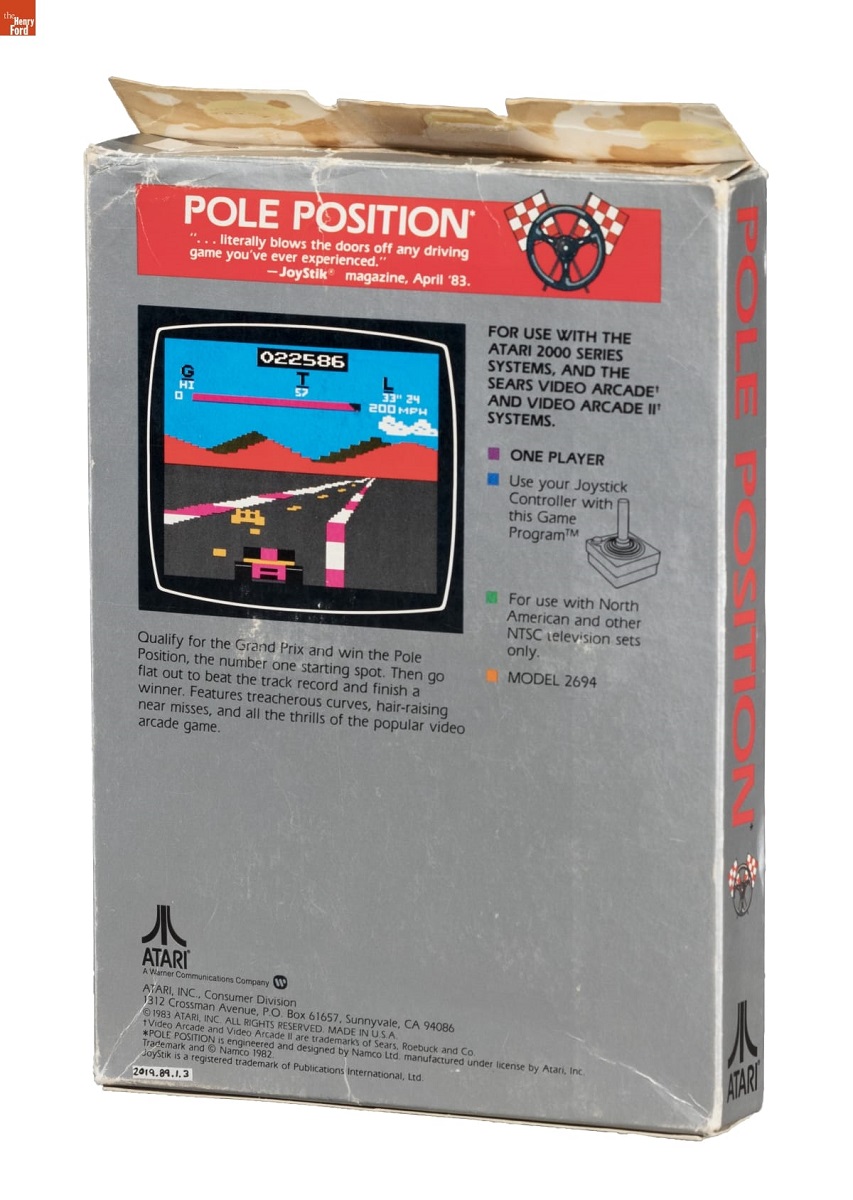 Silver box with text and screenshot from video game of cars on a racetrack 
