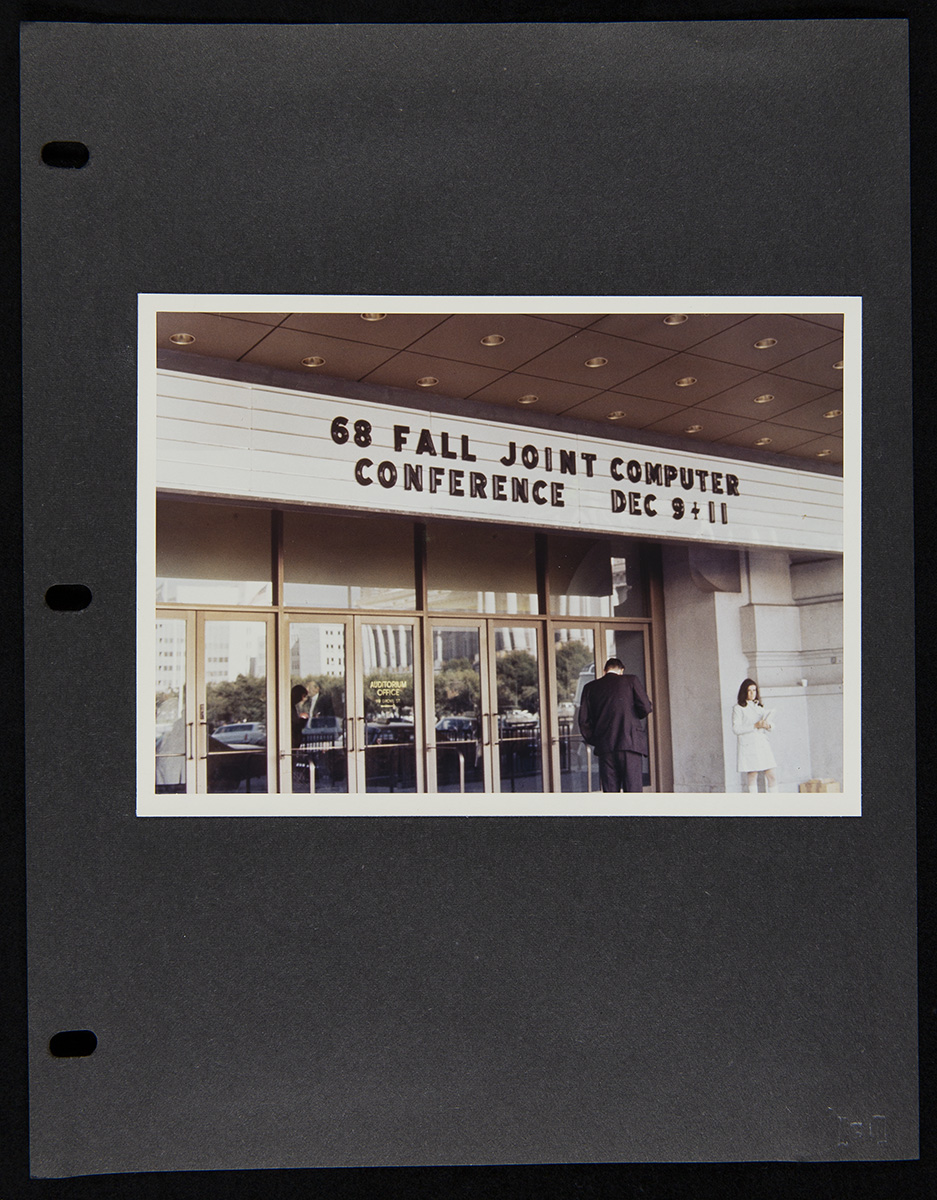 Three-ring binder black-colored page with a photo of entrance doors and a marquee with text; two people in front of doors