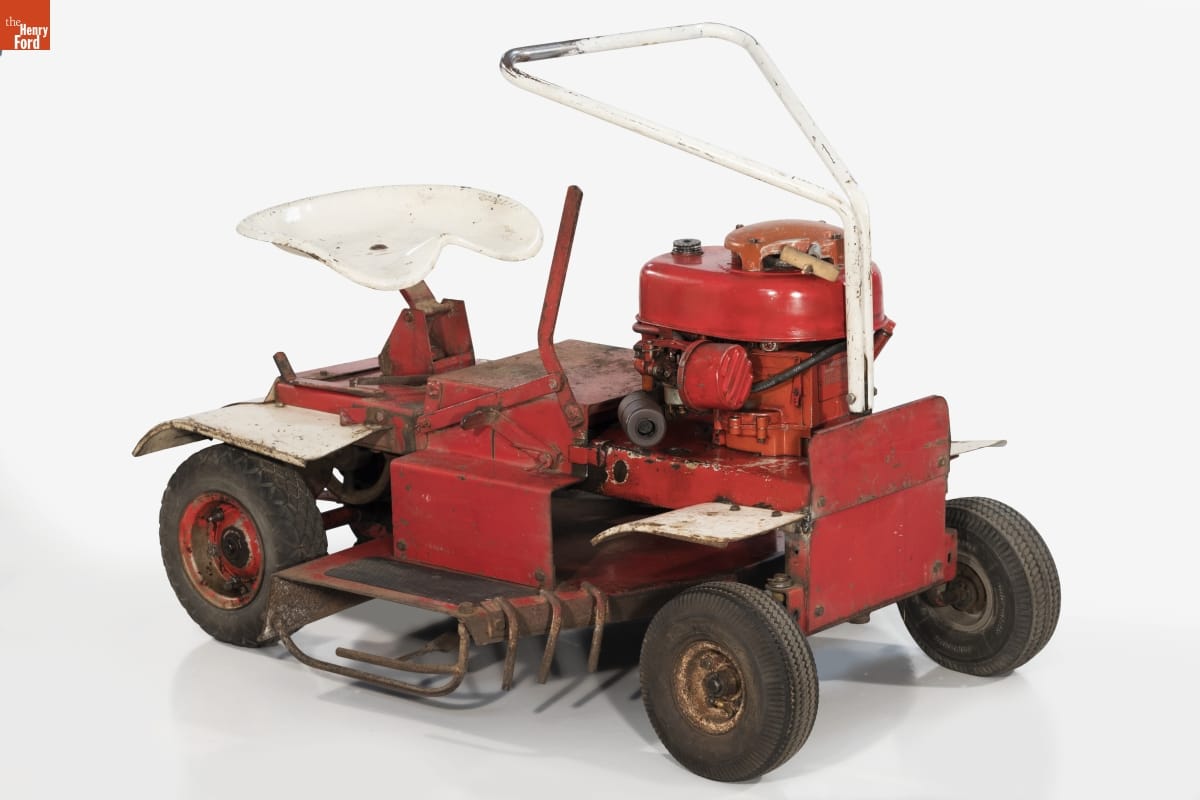 Simple red riding lawnmower with white metal seat and triangular handle