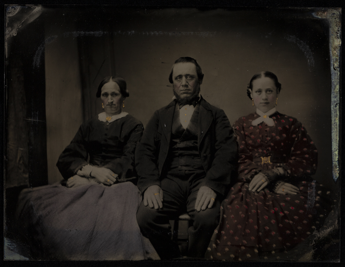 Two women sitting on either side of a seated man