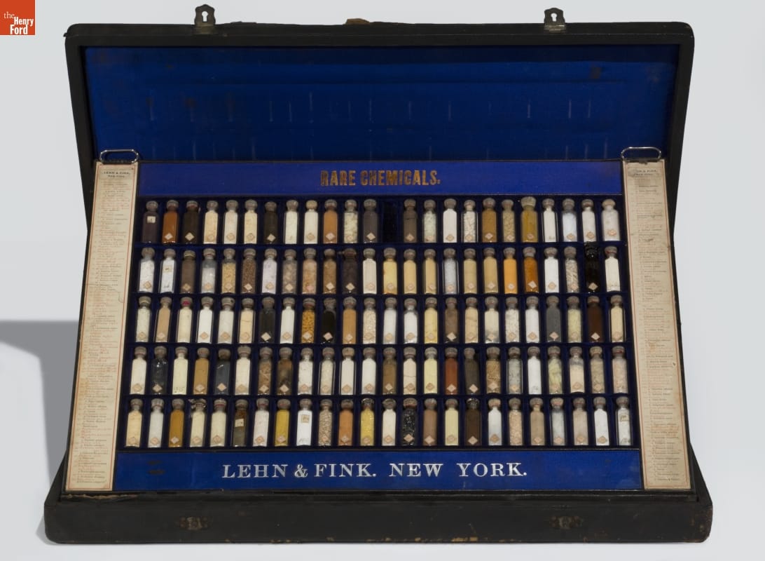 Case lined in blue velvet with insert standing up to display many small vials; also contains text labels