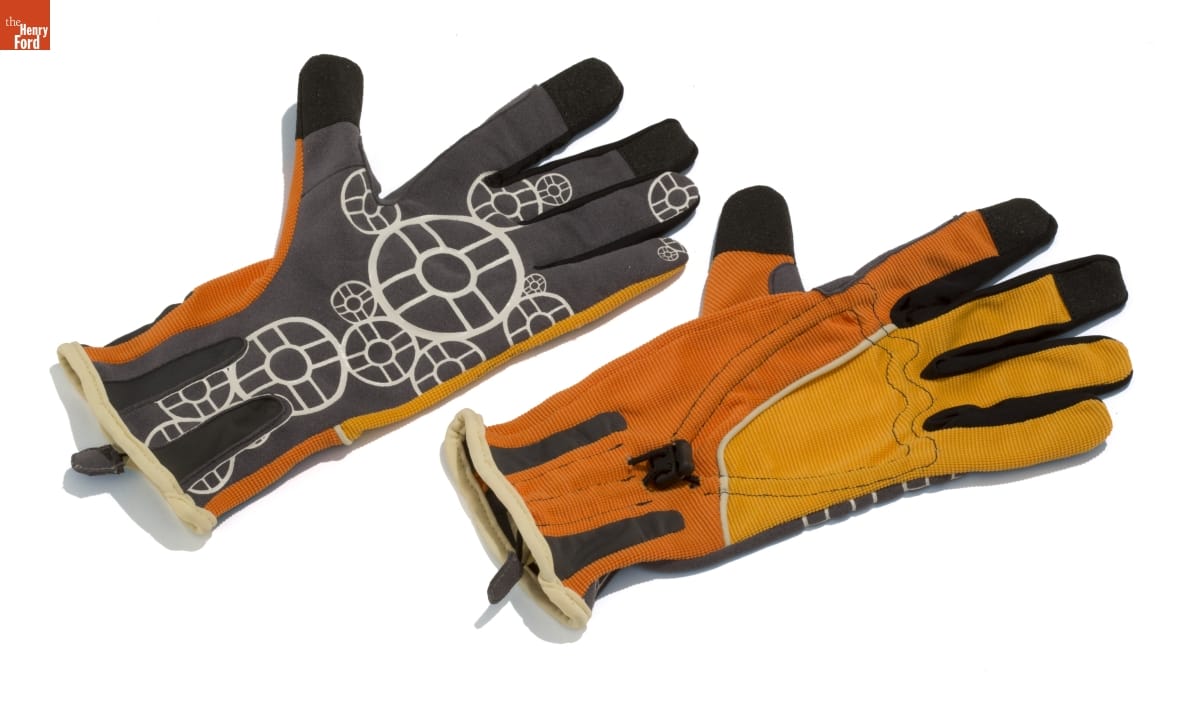 Gloves that are half yellow and half orange on back and gray with white pattern of circles or gears on palms