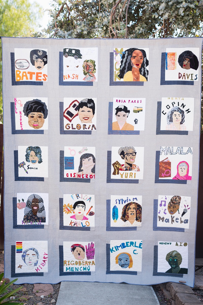 Quilt with gray background on which there are 20 blocks, each depicting a woman's face and containing text with the woman's name