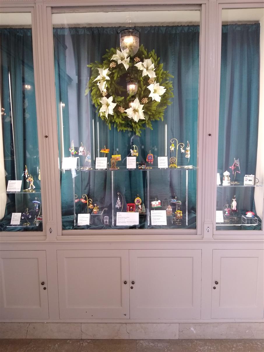 Cabinets with blue curtains, with hanging Christmas wreath and ornaments on stands