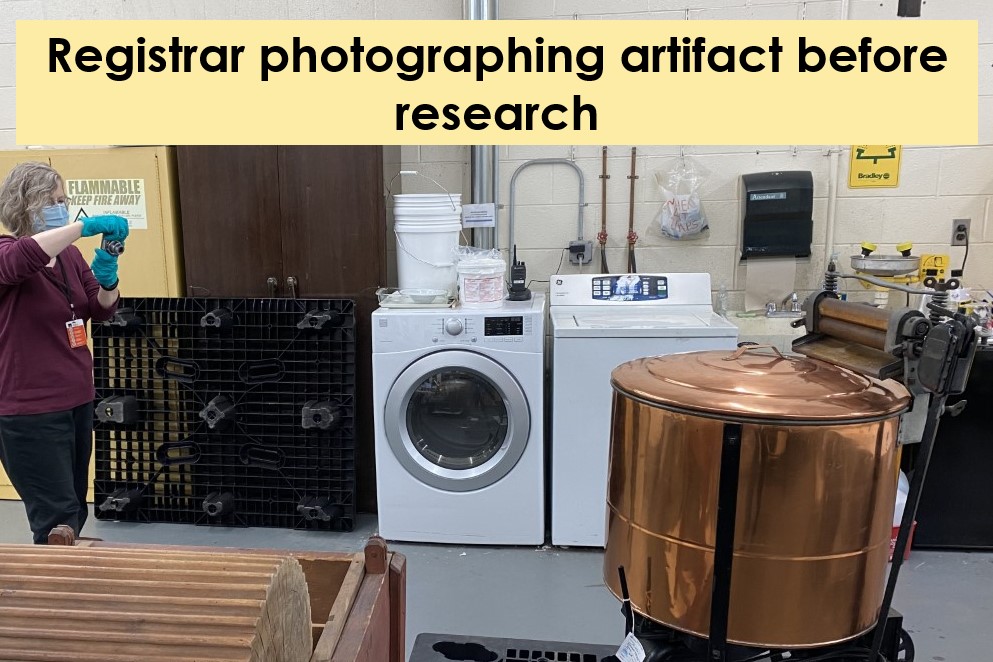 Woman in surgical mask and blue gloves photographing what appears to be a copper tub in front of a washer and dryer