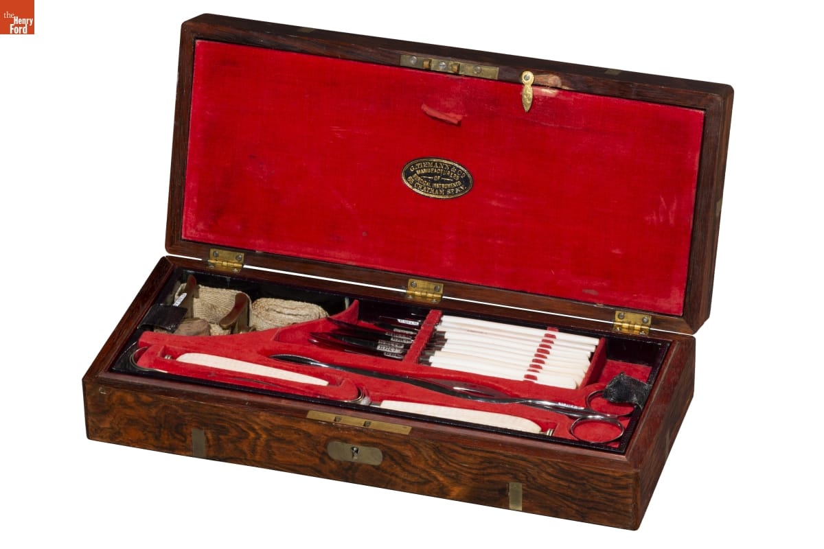 Wooden box lined with red velvet, containing scissors, knives, bandages, and other implements